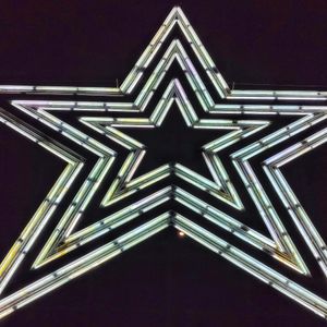 a huge 5-pointed star, its neon outlines are all lit up in white, and it’s a stark contrast to the dark night sky.