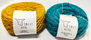 Two cakes of alpaca yarn, the left one (Carmel Sunshine) in bright yellow and the right (Alberta's Pool) a bright teal. Both are Twirl Ditto yarns.
