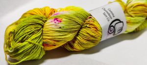 Wool yarn wound in a hank, an amazingly bright neon yellow, with subtle lime gradients and speckles of hot pink throughout.