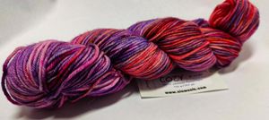 Wool yarn wraped in a hank, in deep jewel tones of orange, purple, and pink.