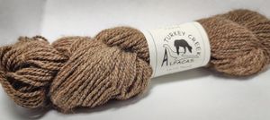 Alpaca yarn wound in a hank, in the fiber's natural dark tan color.